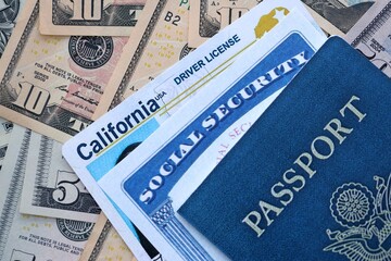 Social security number and California driving license with passport on US dollar money bills close up