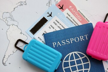 Passport with boarding pass tickets and toy luggage bag on world map close up