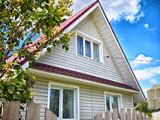 Beautiful house with a red roof and white trim set against a clear blue sky on a sunny day
