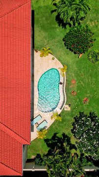 Aerial view of a house with a red roof and a turquoise pool surrounded by lush green vegetation and trees, Sam Roi Yot, Prachuap Khiri Khan, Thailand.