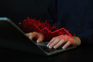 Business person using laptop with red declining stock chart, representing financial loss, market downturn, data analysis, and economic crisis concept in modern digital investment or trading.