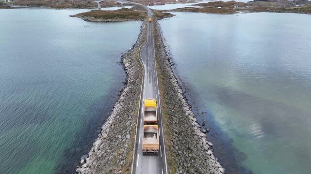 Aerial view of the Storseisundet Bridge, a dramatic structure cutting through the sea with snow-capped mountains in the background, Aver&oslash;y, Norway.