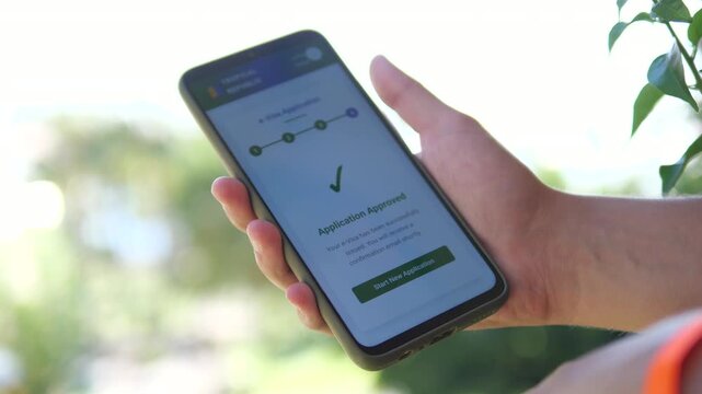 An international travelers hands on a balcony hold a smartphone showing confirmation of a submitted visa application and scheduled appointment. This scene represents modern bureaucratic processes and