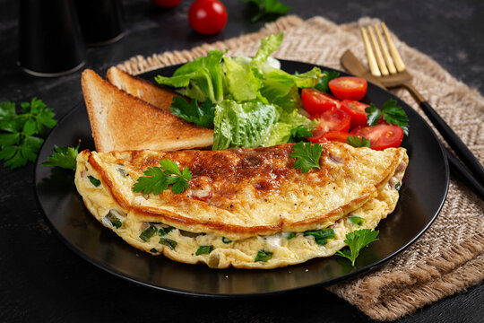 Omelette with cheese, tomatoes and green herbs. Omelette, salad and toast. Keto, ketogenic lunch. Healthy breakfast.