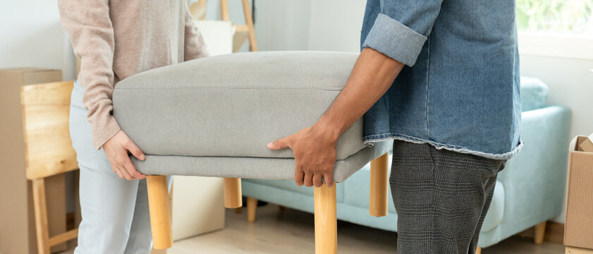 Moving house, relocation. Couple help set sofa and move furniture for new apartment, inside the room was a cardboard box contain personal belongings. move in the new apartment or condominium