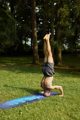 Obraz premium A Man Practicing the Yoga Headstand Pose in Beautiful Nature Surrounded by Lush Green Scenery