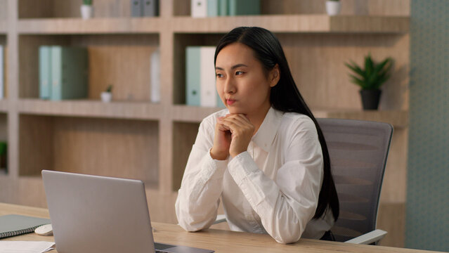 Thoughtful pensive Asian Korean business woman female worker Japanese Chinese businesswoman girl employer entrepreneur thinking ponder decision deep thoughts solution idea gesture work laptop office