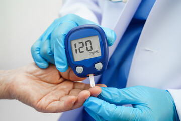 Asian doctor using digital glucose meter for check sample blood sugar level to treatment diabetes.