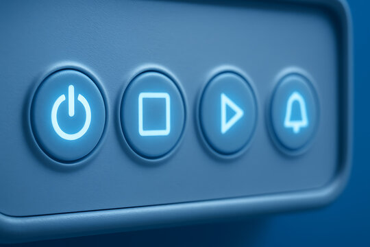 Close-up of illuminated control buttons with power, stop, play, and alert icons glowing in soft blue light, symbolizing modern technology and digital interface design.