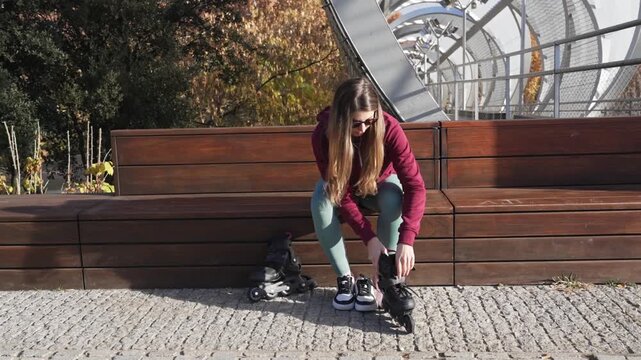 Young woman putting on rollerblades outdoors