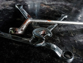 Worn Mechanic's Wrenches Scattered on a Dark, Grungy Workbench. Depicting repair, hard work, and the mechanical industry.