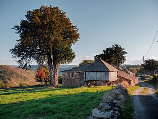 Stone houses in the mountains of A Fonsagrada, Lugo, Galicia, Spain. Traditional Galician mountain village with stone walls wooden details and black slate roofs on a sunny day in northern Spain.