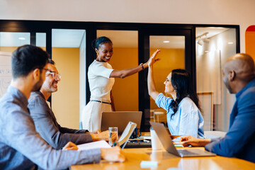Diverse business team celebrating success with a high five during meeting