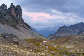 Pink sky over rugged mountain valley stream