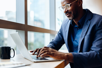 Confident professional man working on a laptop in a bright office setting
