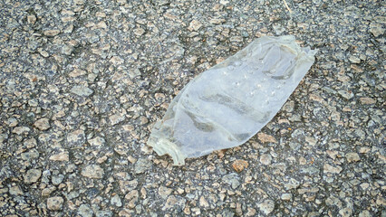 Crumpled Plastic Water Bottle Lying on Rough Pavement: Concept of Environmental Pollution, Waste, and Urban Litter
