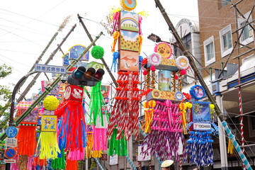 昼間の商店街に飾られた巨大でカラフルな七夕飾りをローアングルで捉えたにぎやかなお祭り風景です