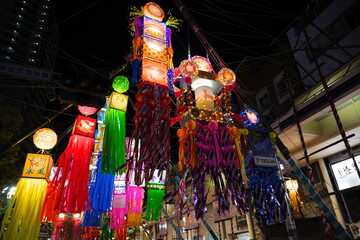 夜の闇に浮かび上がる色鮮やかにライトアップされた巨大な七夕飾りの美しさと幻想的な雰囲気を捉えています