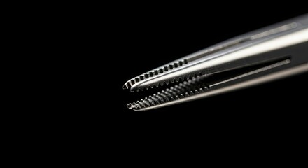 Close-up of surgical instrument with serrated jaws against black background.