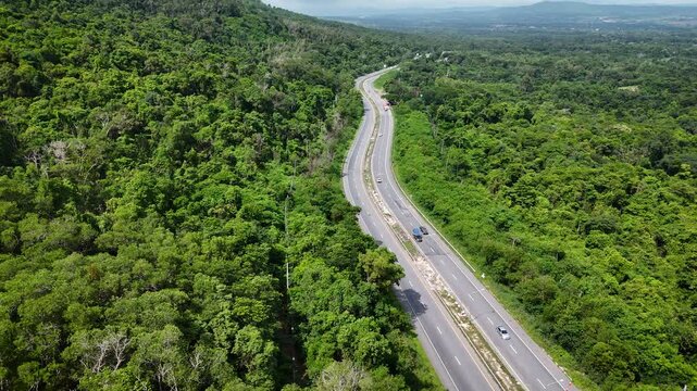 Drone footage of the aerial view of a winding road cutting through lush green forest. Scenic highway number 304 in Thailand links the Bangkok area to Nakhon Ratchasima in the northeastern region