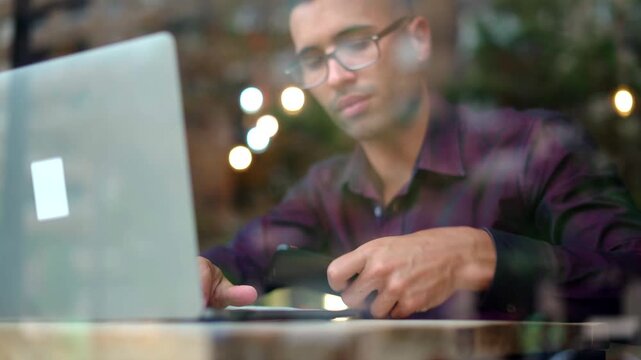 Focused young man working on laptop in modern cafe during evening hours