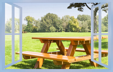 Wooden new picnic table on a green meadow of a public park with trees on background - concept image