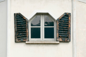 small window with odd shape with worn wooden shutters 