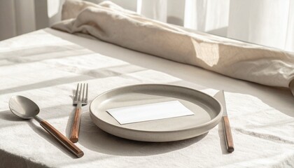 Elegant minimalist table setting with a blank card mockup on a ceramic plate, bathed in natural sunlight. Rustic cutlery on a linen tablecloth for a special event