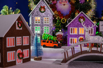 A town with beautiful multi-colored houses with illuminated windows and a bridge with a deer in the center