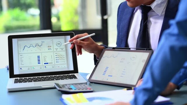 Closeup of professionals analyzing financial data on laptop and tablet in modern office, symbolizing teamwork, analytics - Powered by Adobe