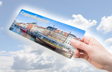 HAND HOLDING AN AIRPLANE TICKET TO COPENHAGEN with a panoramic view of the Nyhavn city the most famous landmark in Copenhagen (Europe - Denmark)