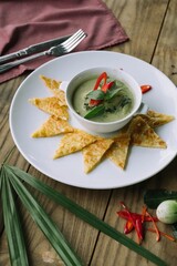 A gourmet Thai cuisine dish with a creamy green curry sauce. The dish is beautifully presented on a plate