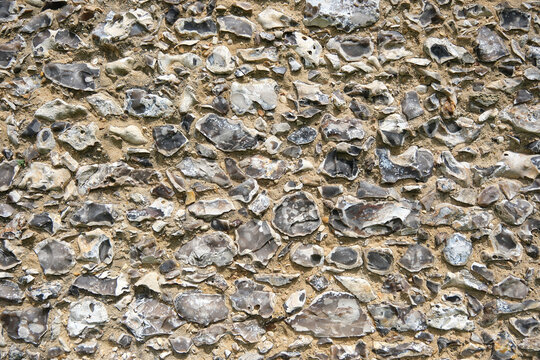 Closeup of a traditional flint wall showing natural stone texture and rustic pattern.