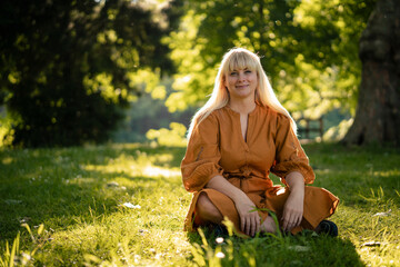 Smiling blond woman sitting on grass