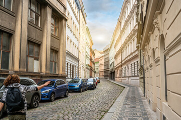 Prague, Czech Republic, August 7, 2023. Street photography exploring the old town: a young man with curly hair and a backpack points the way past the colorful period buildings. Travel destinations.