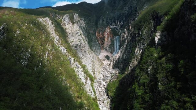 Clouds covering the mountain peaks, huge waterfall on the side of the mountain