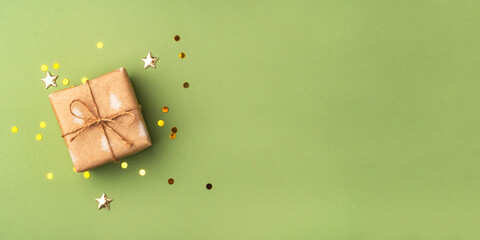 A Christmas gift wrapped in eco-friendly packaging on a green background with golden confetti