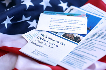 Permanent resident green card in envelope and guide for new immigrants lies on US flag close up