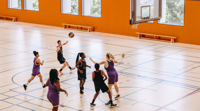 Female basketball players playing an intensive game in a dynamic indoor court