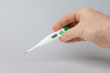 Hand holding digital thermometer displaying temperature reading, symbolizing health monitoring during new strain of virus outbreak. copy space