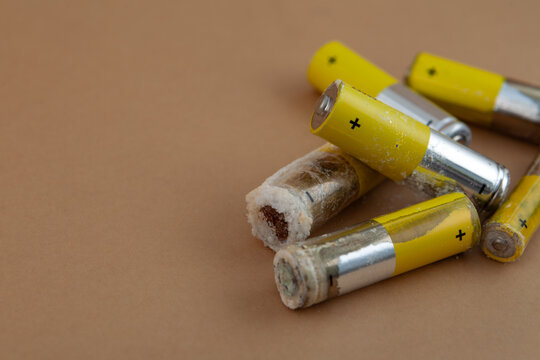 Old used batteries. Oxidized and leaked AA alkaline batteries. White powder Potassium hydroxide was formed leakage of alkaline electrolyte. Caustic powder can be irritate skin and mucous membranes