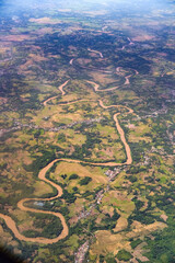 Winding river snakes through lush green valleys and farmland, creating a mesmerizing natural pattern visible from above that captures the raw beauty of rural landscapes and flowing waterways.