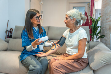 Nurse checking senior woman blood pressure at home