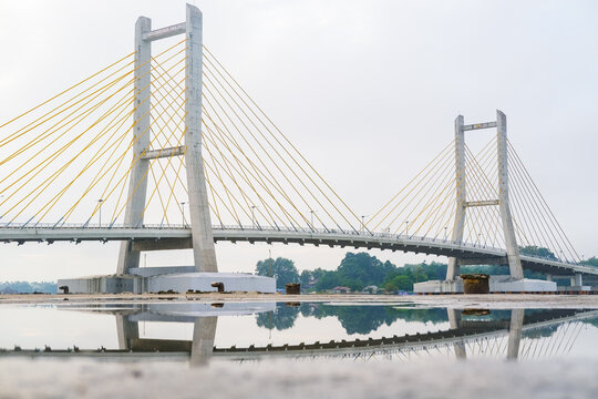 Cable-stayed bridge spanning across Kendari Bay, showcasing modern engineering and elegant design that connects the city&rsquo;s shores with scenic reflection on calm waters.