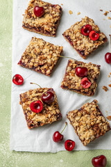 Cherry oatmeal crumble bars. Backed cherry crisp. Quick and easy homemade sweet red berry squares with streusel. Crumble fruit cake or pie. Wholesome and healthy breakfast. Home cooking.