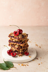 Stack of baked oatmeal crumble squares with fresh cherry. Cherry oatmeal crumble bars. Quick and easy homemade red berry pie with streusel. Crumble fruit cake. Home cooking. Copy space.