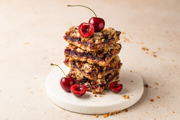 Stack of baked oatmeal crumble squares with fresh cherry. Cherry oatmeal crumble bars. Quick and easy homemade red berry pie with streusel. Crumble fruit cake. Home cooking.
