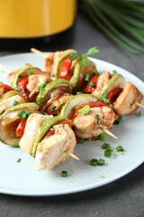 Tasty skewers with chicken, vegetables and green onion on grey table, closeup