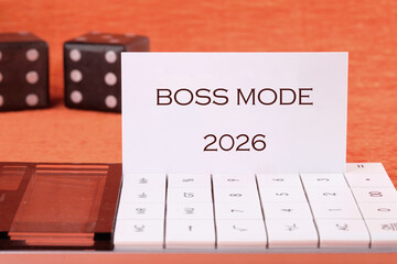 A sleek workspace shows a modern device displaying BOSS MODE alongside dice. This setup exudes motivation and inspires productivity for the year 2026