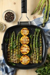 Delicious grilled vegetables with spices in pan on wooden table, flat lay